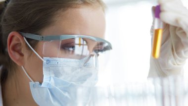 Modern laboratuvar veya hastanede plastik tıbbi tüplerle çalışan araştırmacı, doktor, bilim adamı veya laboratuvar asistanı