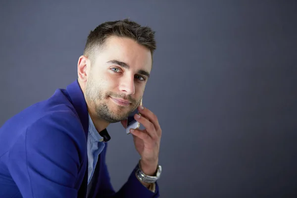 Joven empresario sentado aislado sobre fondo gris. —  Fotos de Stock