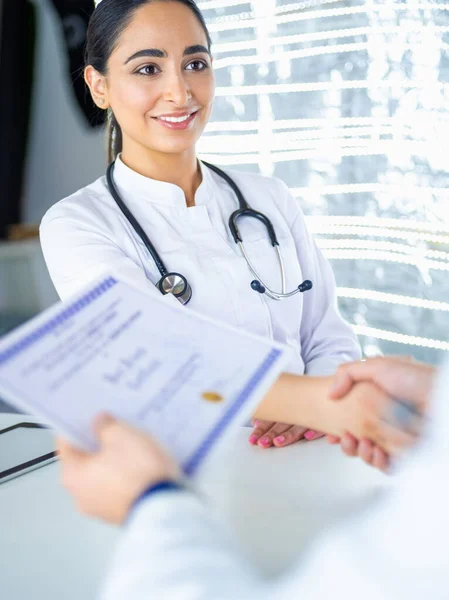 Jovem mulher médica handshaking no escritório — Fotografia de Stock