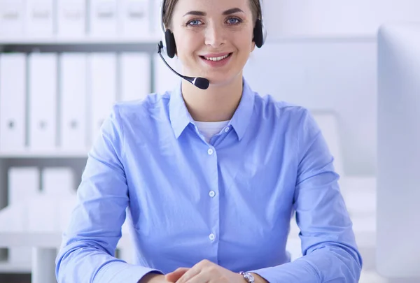 Ernstige mooie jonge vrouw die werkt als support telefoon operator met headset in het kantoor — Stockfoto