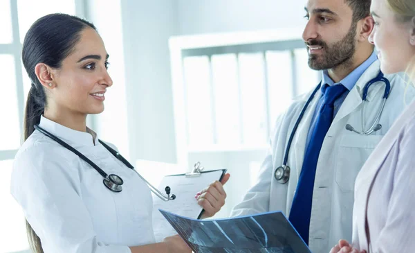 Een vrouwelijke arts laat een andere dokter een röntgenfoto zien in haar kantoor. — Stockfoto