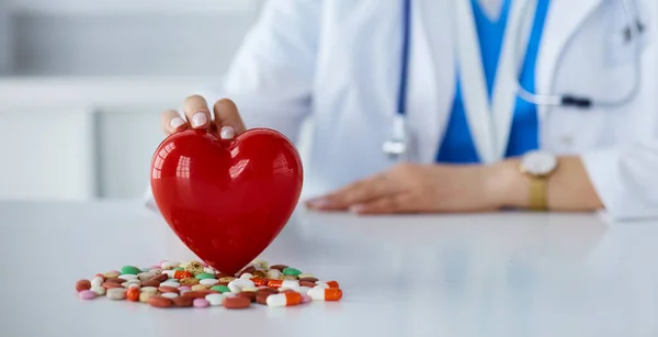 Un médico con estetoscopio examinando el corazón rojo, aislado sobre fondo blanco — Foto de Stock