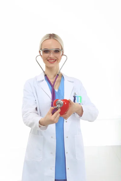 Médica jovem segurando um coração vermelho, isolado em fundo branco. Mulher médica — Fotografia de Stock