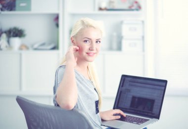 Kanepede oturup dizüstü bilgisayar kullanan güzel bir kadın.