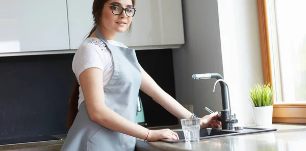 Vrouw die een glas water vult uit een roestvrijstalen kraan of kraan — Stockfoto