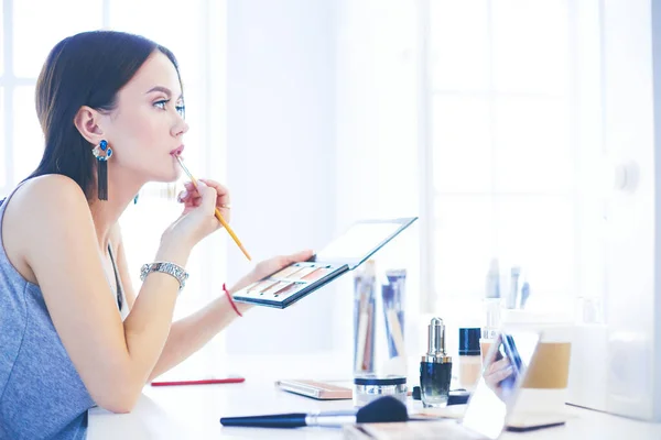 Mujer morena aplicando maquillaje para una cita nocturna frente a un espejo —  Fotos de Stock