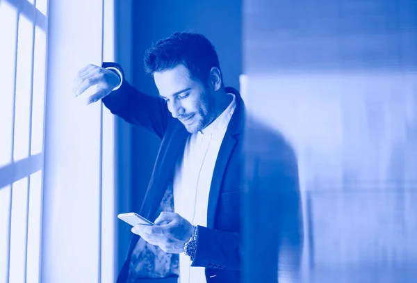 Hombre de negocios en traje hablando por teléfono y mirando hacia otro lado cerca de la ventana . — Foto de Stock