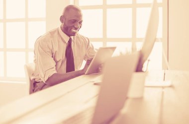 Kulaklıklı Afro-Amerikan işadamı laptopuyla çalışıyor.