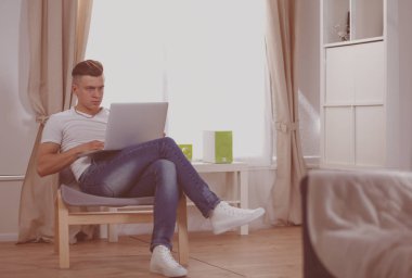 Evdeki koltukta oturan yakışıklı, kendine güvenen adam.