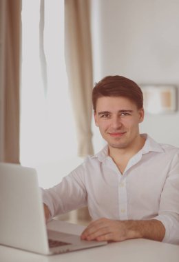 Ofis çalışanı adamın dizüstü bilgisayar kullanarak ofis masasında oturan portresi