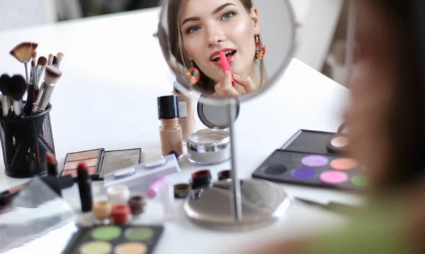 Joven hermosa mujer haciendo maquillaje cerca del espejo —  Fotos de Stock