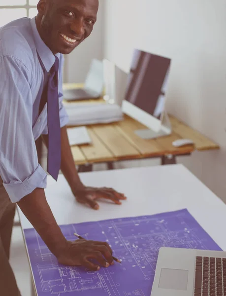 Africký americký architekt pracující s počítačem a plány v kanceláři — Stock fotografie