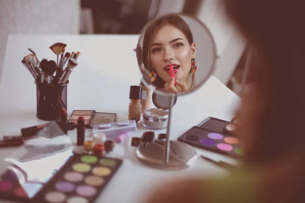 Joven hermosa mujer haciendo maquillaje cerca del espejo —  Fotos de Stock