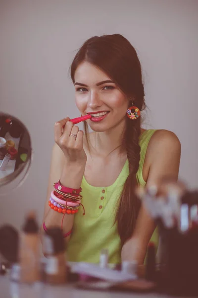 Joven hermosa mujer haciendo maquillaje cerca del espejo —  Fotos de Stock