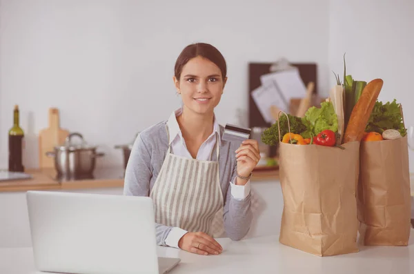 Mujer guapa disfrutando de una taza de café mientras se relaja con su computadora portátil en la cocina — Foto de Stock