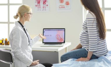 Hastanede doktorla gülümseyen güzel bir hamile kadın.