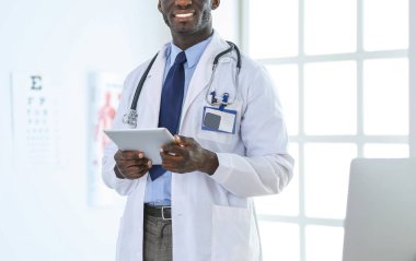 Tablet bilgisayarlı siyahi bir doktor hastanede bekliyor.