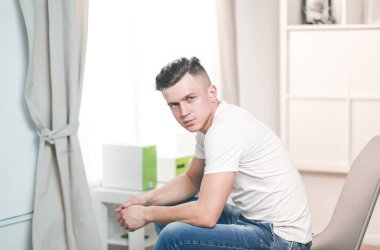 Evdeki koltukta oturan yakışıklı, kendine güvenen adam.