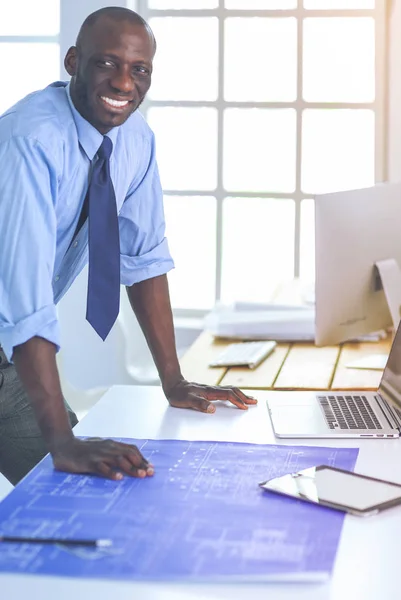 Arquitecto afroamericano trabajando con computadoras y planos en la oficina —  Fotos de Stock