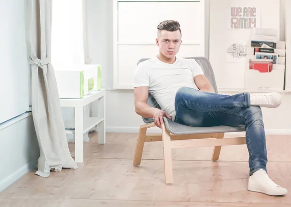 Schöner selbstbewusster Mann sitzt zu Hause im Sessel — Stockfoto