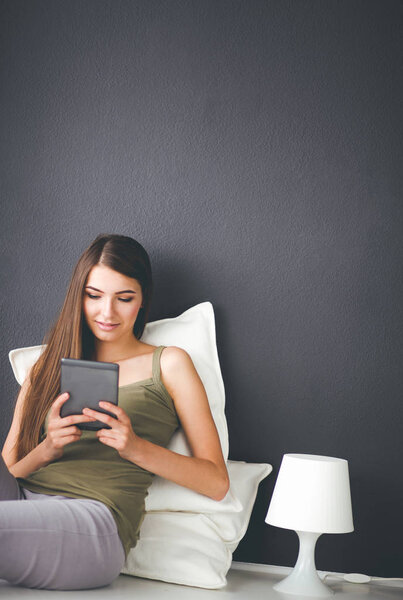 Женщина, сидящая на полу с цифровым планшетом