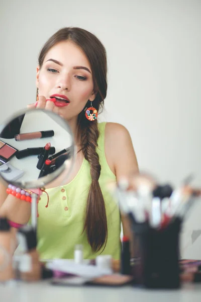 Joven hermosa mujer haciendo maquillaje cerca del espejo — Foto de Stock