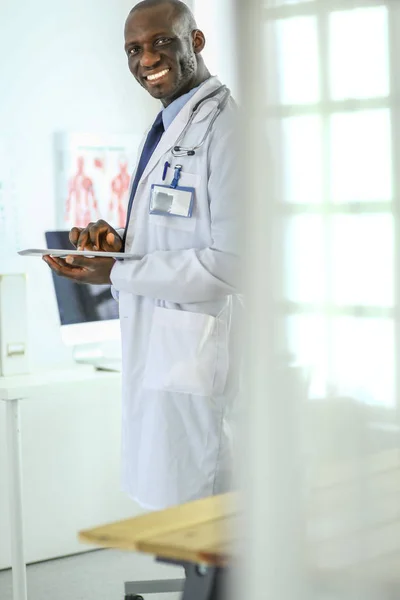 Male black doctor worker with tablet computer standing in hospital