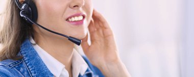 Ofiste kulaklık takıp laptopla çalışan mutlu, genç bir kadın.