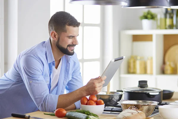 男人们在家里的厨房里按照数码平板电脑的配方烹调美味而健康的食物 — 图库照片