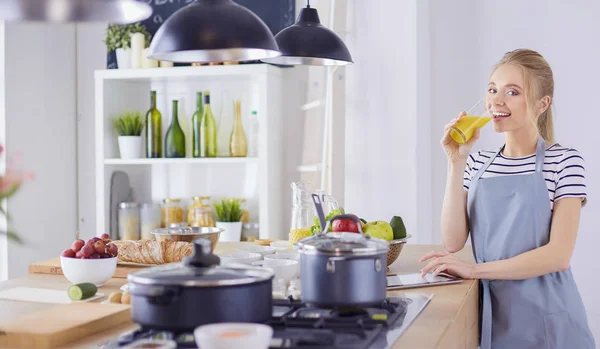 Çekici kadın mutfakta dikilirken elinde bir bardak portakal suyu tutuyor. — Stok fotoğraf