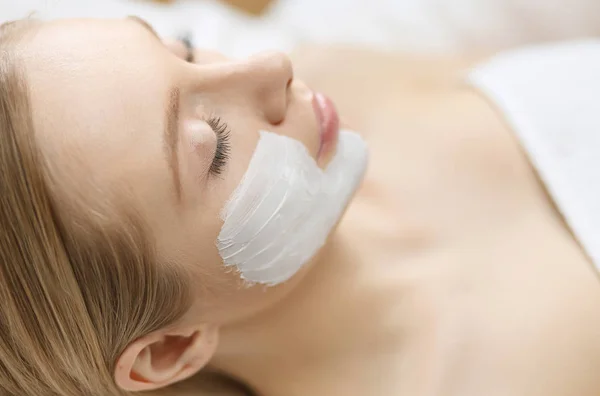 Young beautiful girl receiving pink facial mask in spa beauty salon — Stock Photo, Image