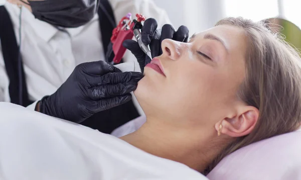 Cosmetólogo aplicando maquillaje permanente en las cejas —  Fotos de Stock