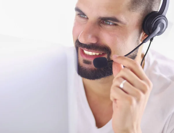 Retrato de un joven con un auricular frente a una computadora portátil — Foto de Stock