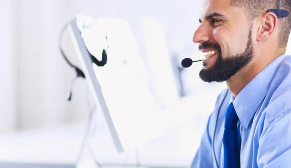 Gelukkige zakenman met headset aan het bureau in modern kantoor — Stockfoto