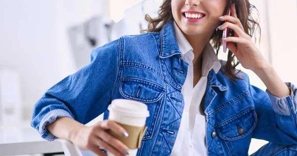 Mujer joven en la cafetería bebiendo café y hablando por teléfono móvil — Foto de Stock