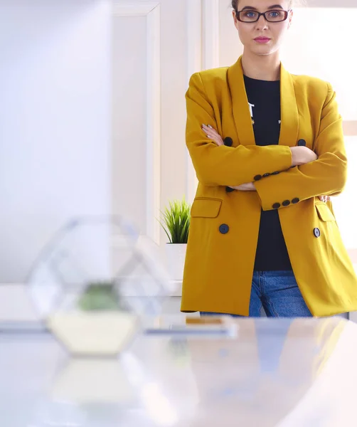 Retrato de una hermosa mujer de negocios de pie cerca de su lugar de trabajo —  Fotos de Stock