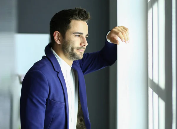 Retrato del joven diseñador frente a la computadora portátil y el ordenador mientras trabaja . — Foto de Stock