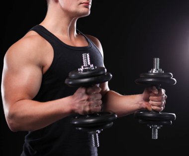 Karanlık duvarda stil sahibi üstsüz bir adam.