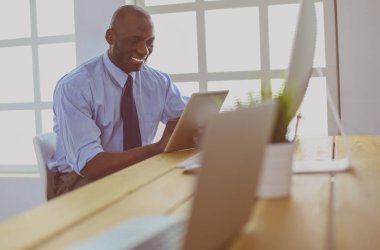 Kulaklıklı Afro-Amerikan işadamı laptopuyla çalışıyor.