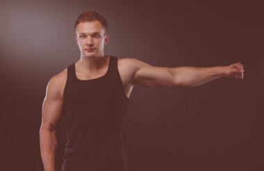 Karanlık duvarda stil sahibi üstsüz bir adam.