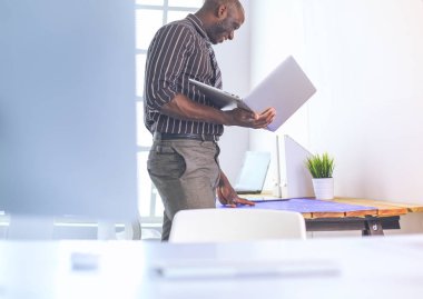 Ofiste bilgisayar ve planlarla çalışan Afrikalı Amerikalı bir mimar.