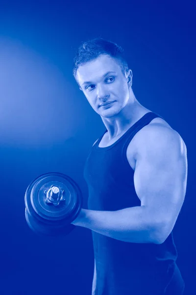Muscular guy doing exercises with dumbbells over dark background — 스톡 사진
