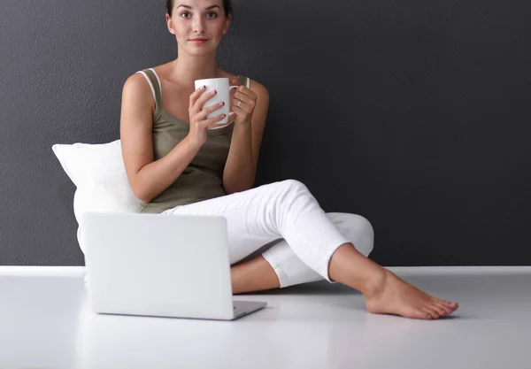 En vacker ung frisk sittande på golvet med en kopp te eller kaffe leende. isolerad på vit bakgrund — Stockfoto
