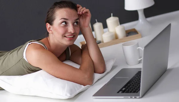 Genç bir kadın ile bir dizüstü bilgisayar yerde yatarken — Stok fotoğraf