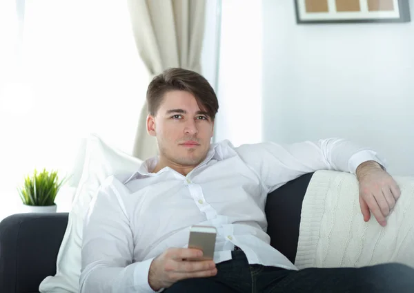 Pohledný mladý muž doma pomocí smartphonu — Stock fotografie