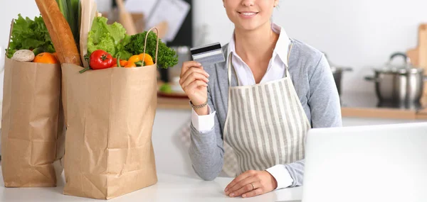 Snygg kvinna njuter av en kopp kaffe och samtidigt koppla av med sin laptop i köket — Stockfoto