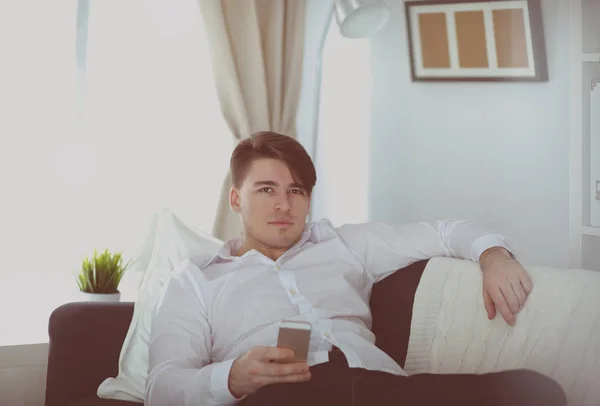 Красивый молодой человек, использующий смартфон дома — стоковое фото