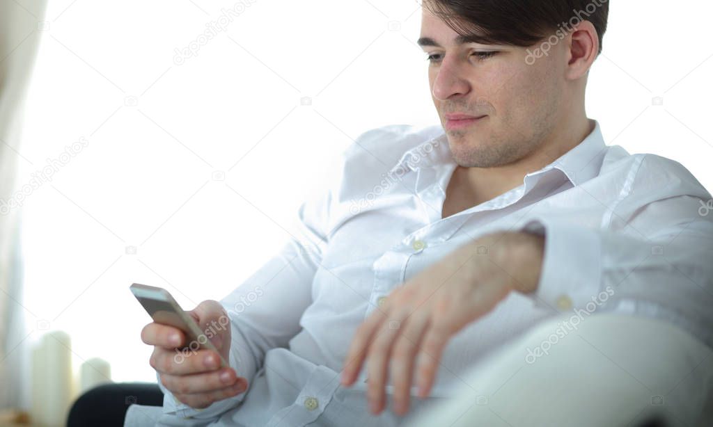 Handsome young man using smartphone at home