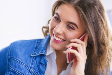 Kafede kahve içip cep telefonuyla konuşan genç bir kadın.