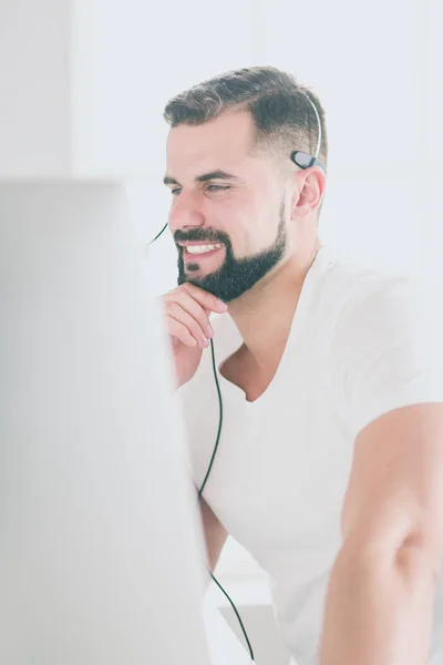 Retrato de un joven con un auricular frente a una computadora portátil —  Fotos de Stock